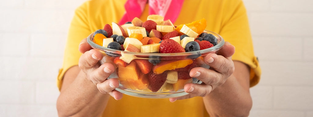 A person holding out a bowl of fresh fruit