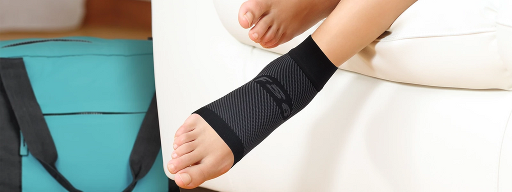 Person relaxing on the couch wearing a compression foot sleeve