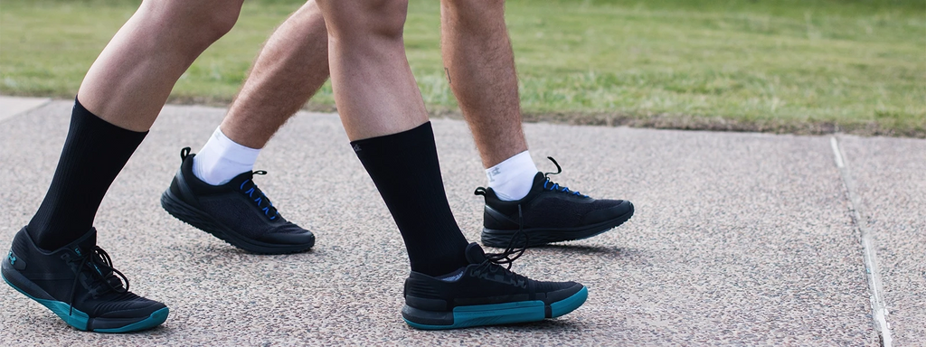 Two people walking on the side walk while wearing wellness socks from OrthoSleeve