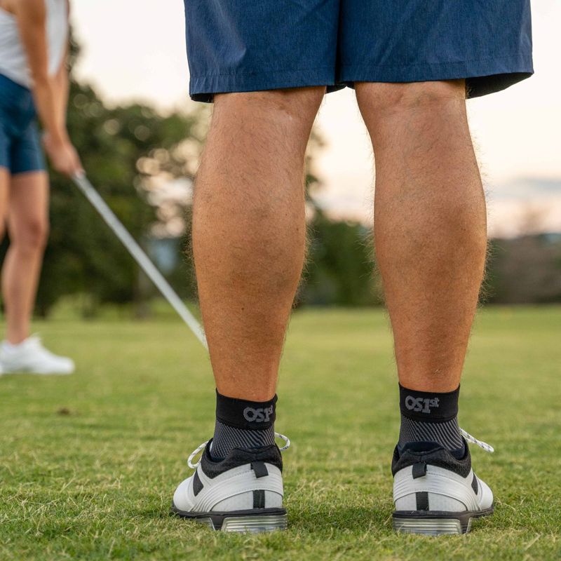 Man wearing a pair of black OrthoSleeve Plantar Fasciitis Foot Sleeves while golfing
