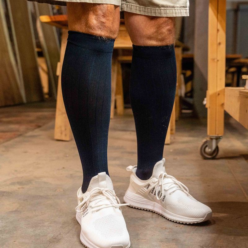 Man wearing a pair of navy OrthoSleeve Medical Grade Compression Socks while working