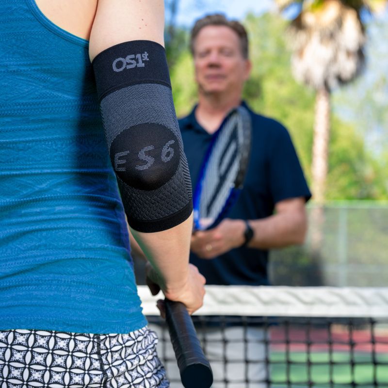 Person wearing the OrthoSleeve Elbow Bracing Sleeve in Black while playing tennis