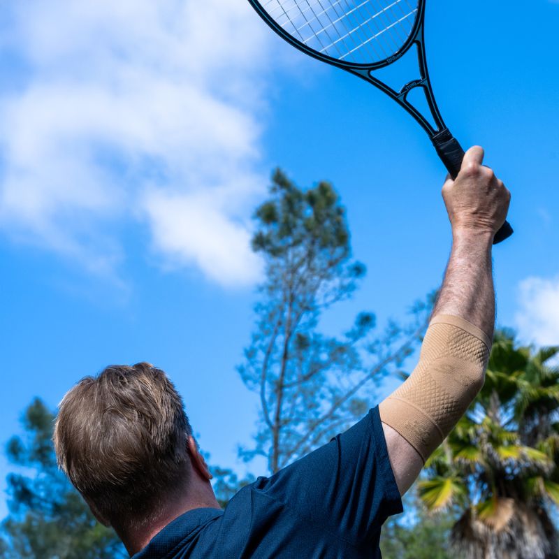 Person wearing the OrthoSleeve Elbow Bracing Sleeve in Tan while playing tennis