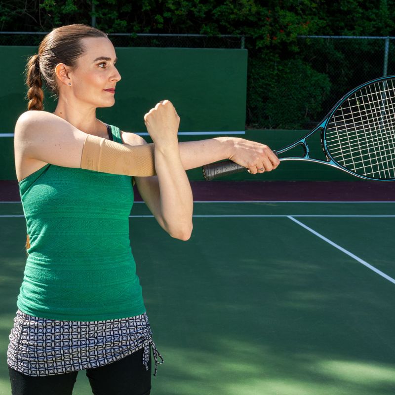 Person wearing the OrthoSleeve Elbow Bracing Sleeve in Tan while playing tennis