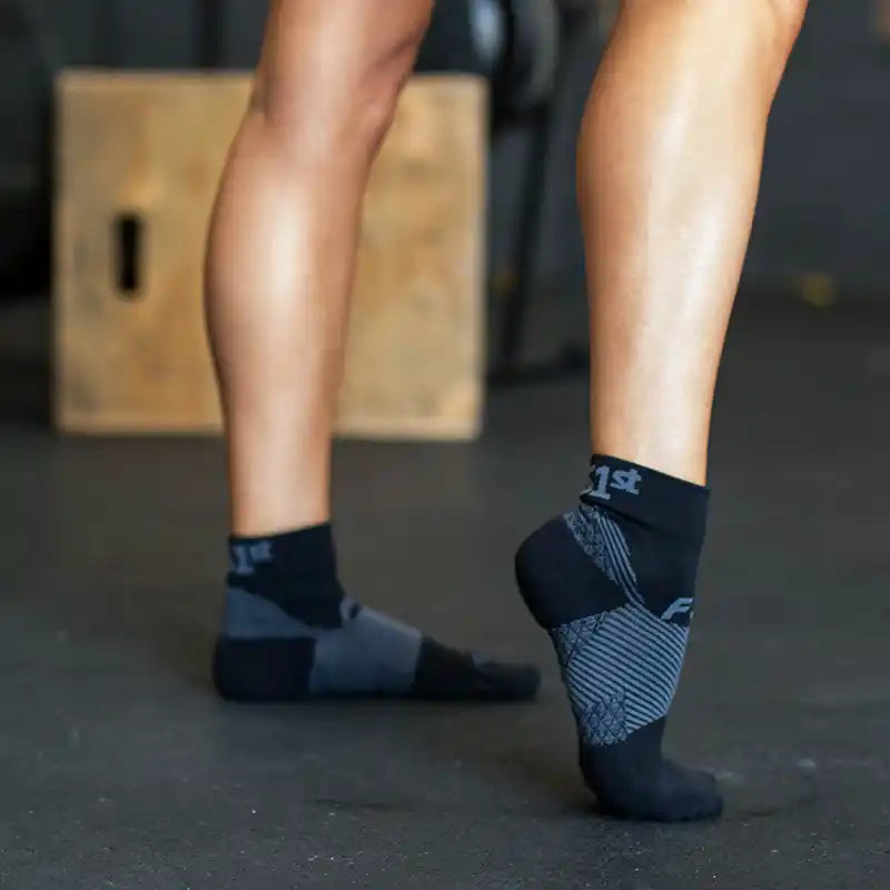 Image of a woman wearing Plantar Fasciitis Socks and flexing her right foot at a gym
