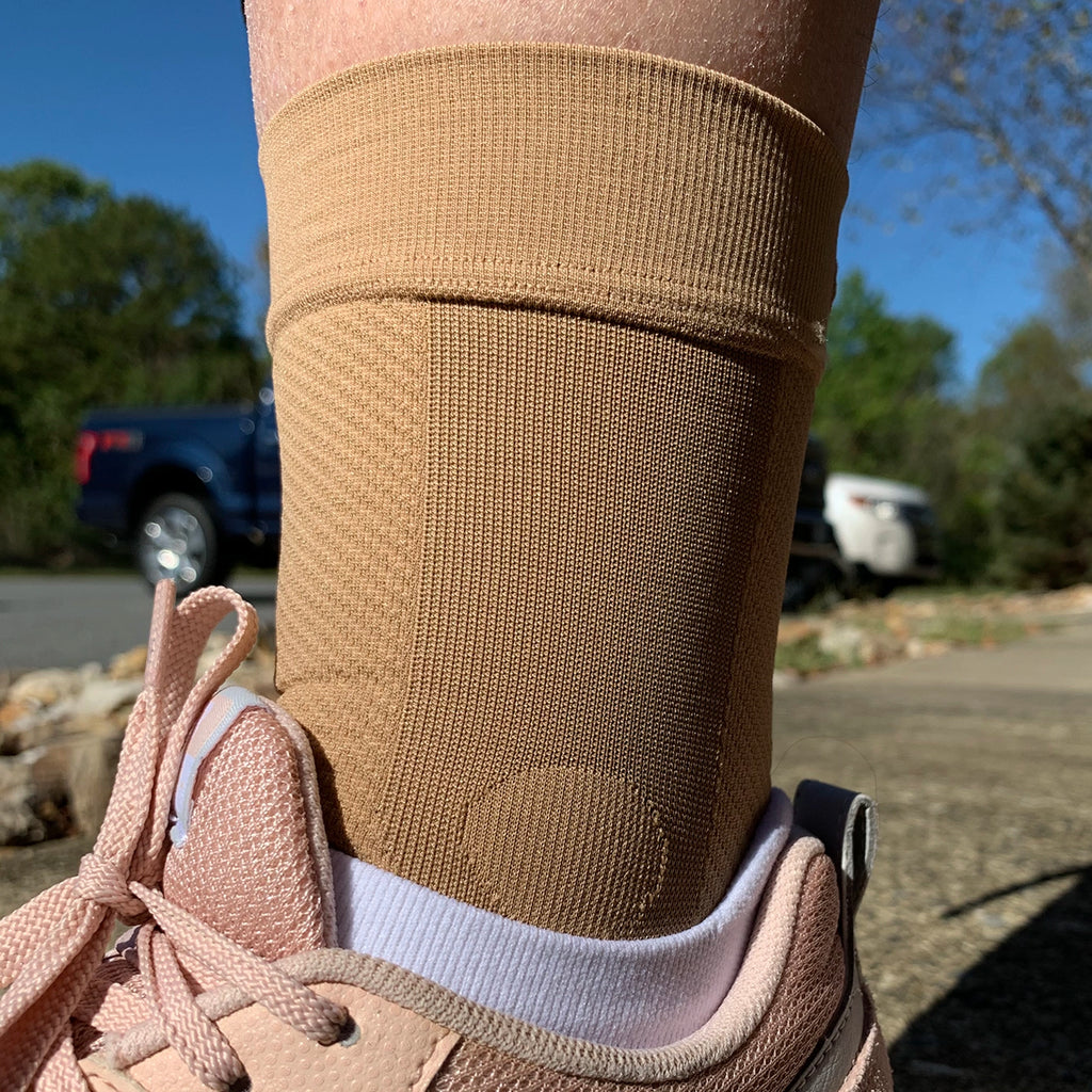 Close up of a tan ankle brace being worn with sneakers