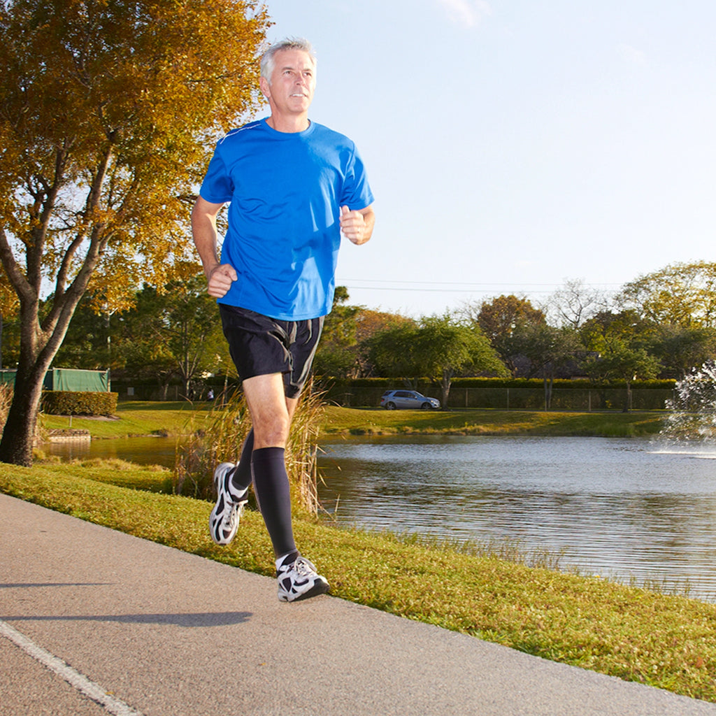 Man running in a park while wearing the compression leg sleeves