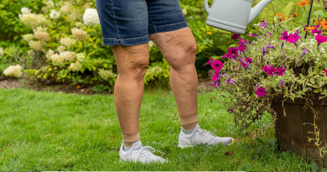 Woman wearing the OrthoSleeve foot sleeves while watering the flowers