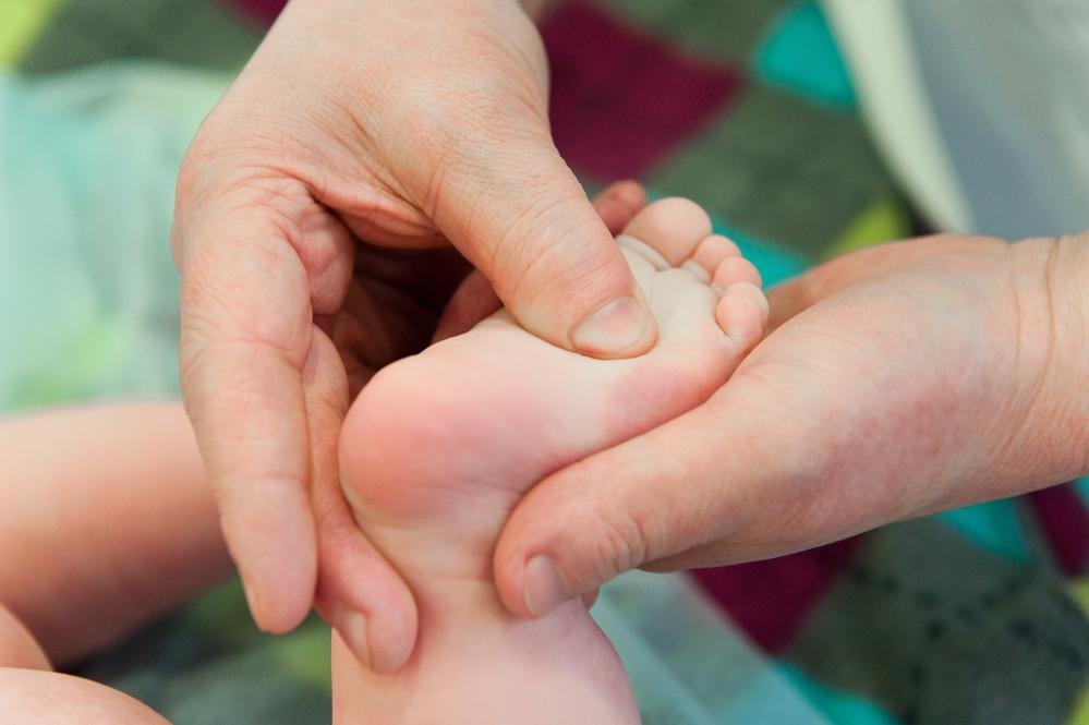 Hand pressing on a baby's flat foot