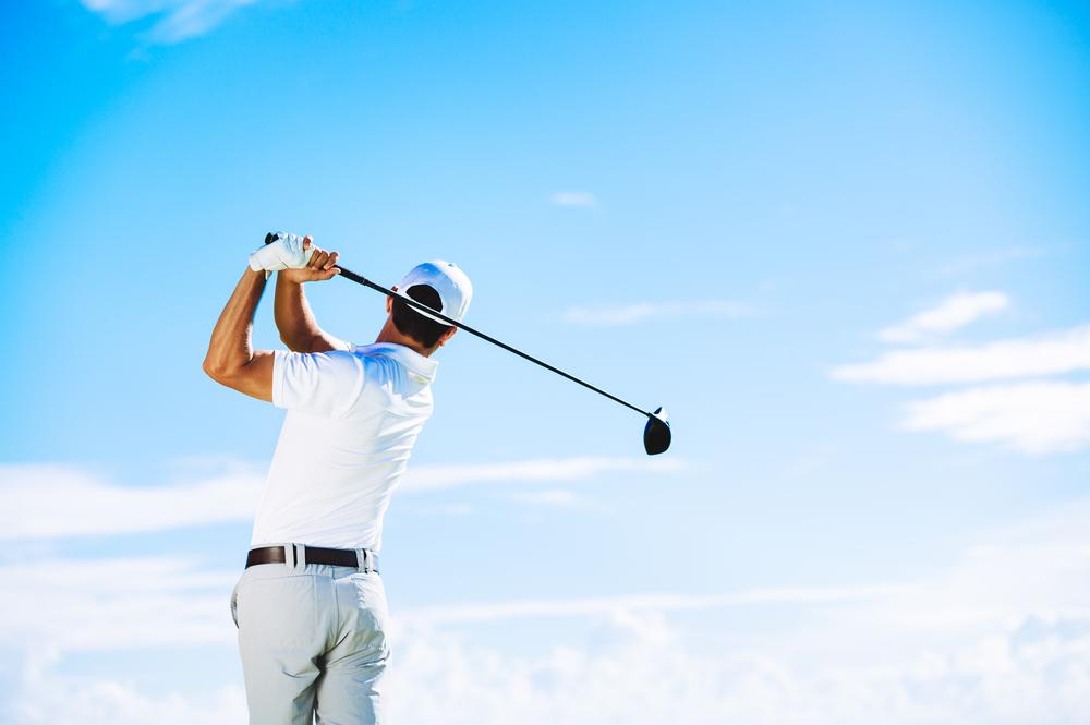 Man swinging golf club to hit the ball toward the sky