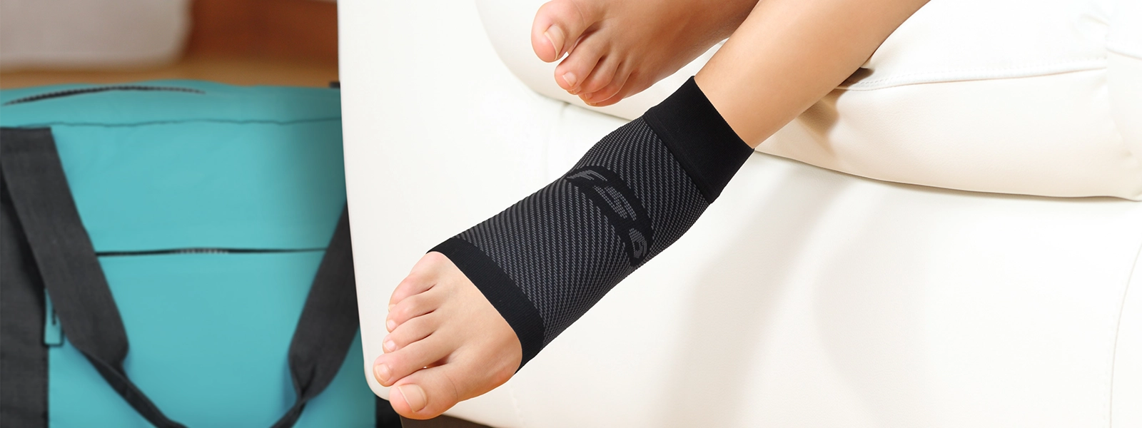 A woman's legs resting on the couch with a compression foot sleeve on