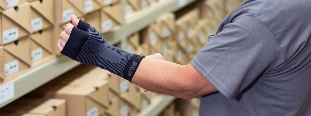 Person wearing a compression wrist sleeve while working in a warehouse