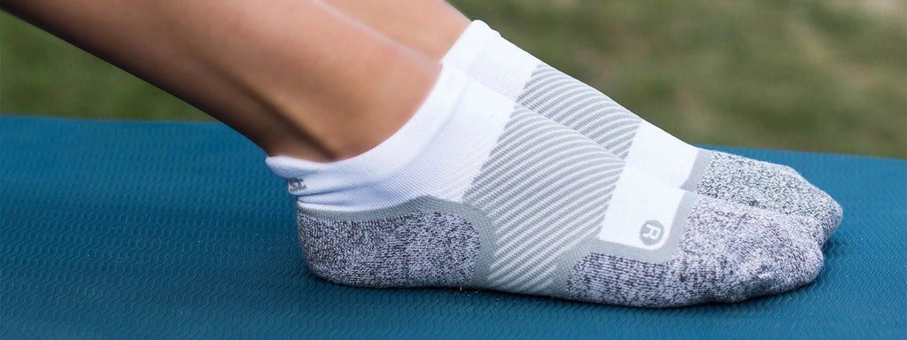 Close up of feet wearing the wellness socks while on a yoga mat