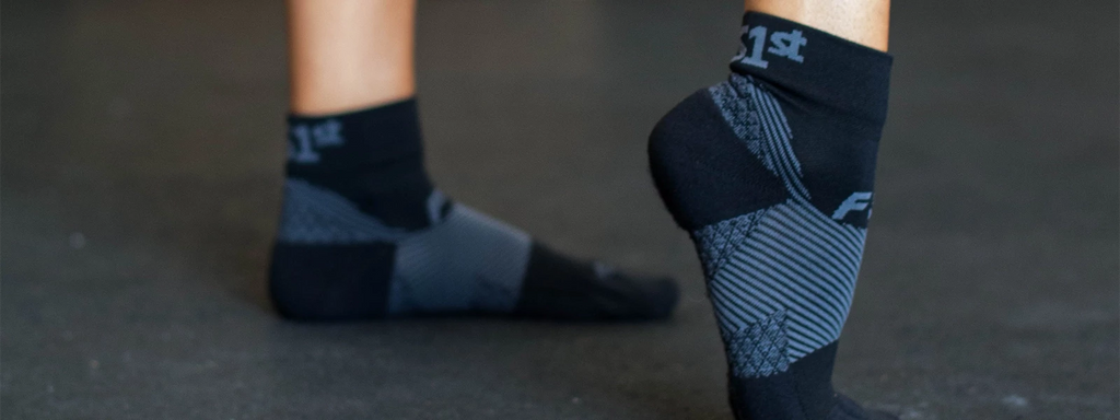 Person standing and flexing one foot while wearing the Plantar Fasciitis socks
