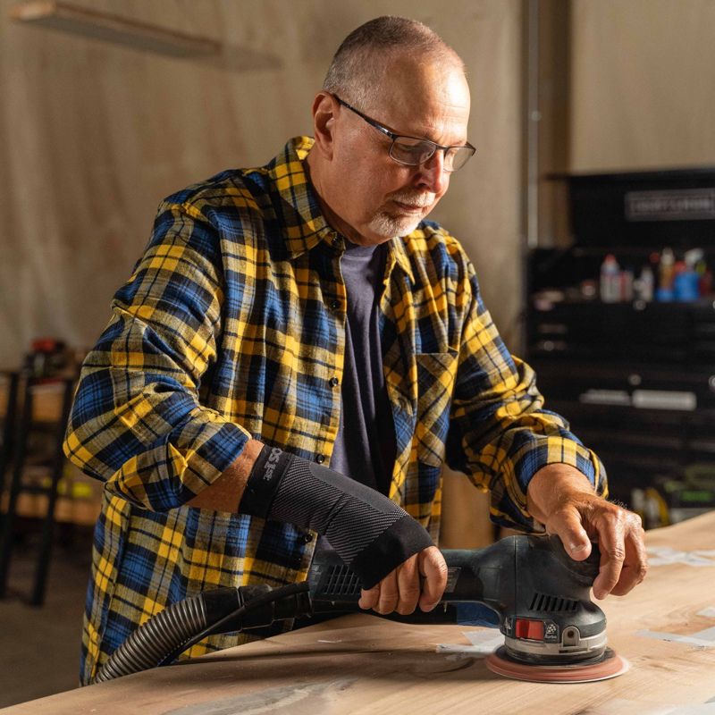 Man wearing the black OrthoSleeve Compression Wrist Sleeve while working