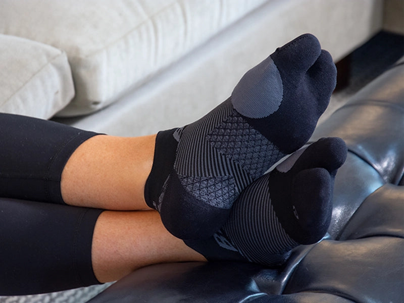 Woman with her feet up, relaxing on the couch with split-toe bunion socks on
