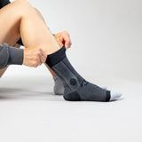 Person putting on black ankle sleeve on a white background