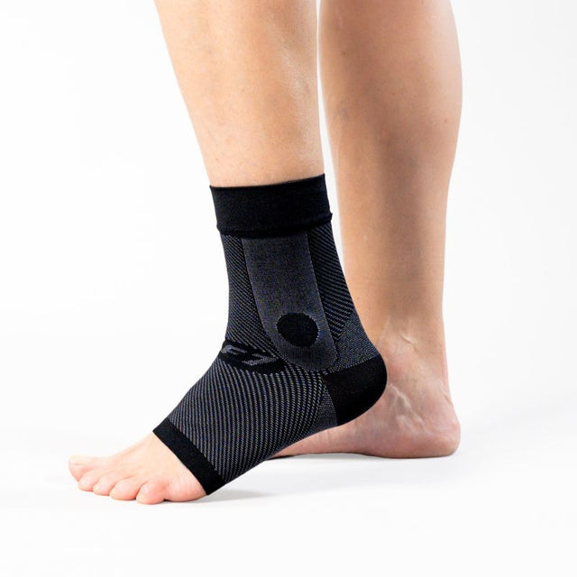 Black ankle sleeve on a person's foot against a white background