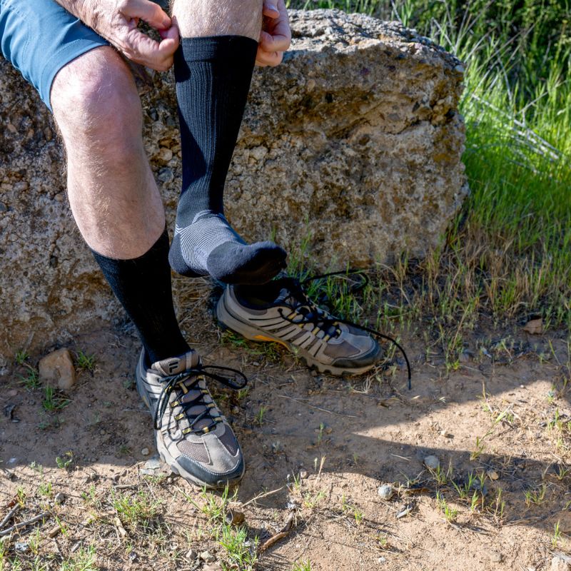 Man wearing the OrthoSleeve Plantar Fasciitis Crew Socks in black while hiking
