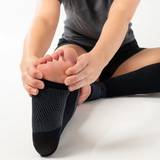Person sitting and stretching while wearing the FS6+ Leg Sleeves in black