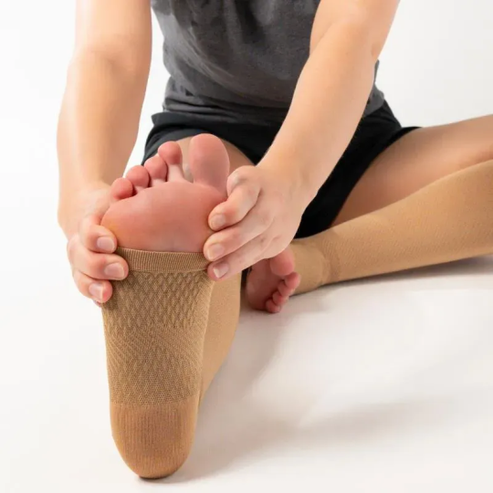 Person sitting and stretching while wearing the FS6+ Leg Sleeves in tan