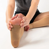Person sitting and stretching while wearing the FS6+ Leg Sleeves in tan