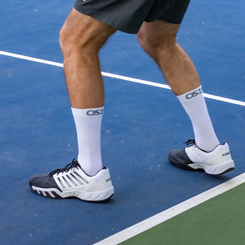 Man playing pickleball while wearing the OS1st White Pickleball Crew length socks
