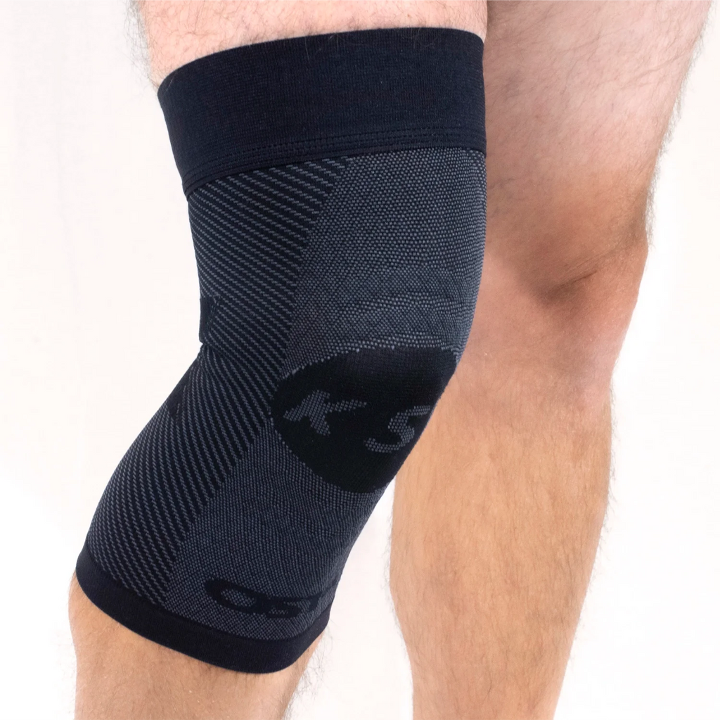 Close up of a man's legs. The left leg is wearing a black compression knee brace
