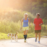 A woman wearing compression bracing socks while holding a dog on a leash 