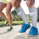 A close up of a male runner's legs wearing the compression bracing socks in grey