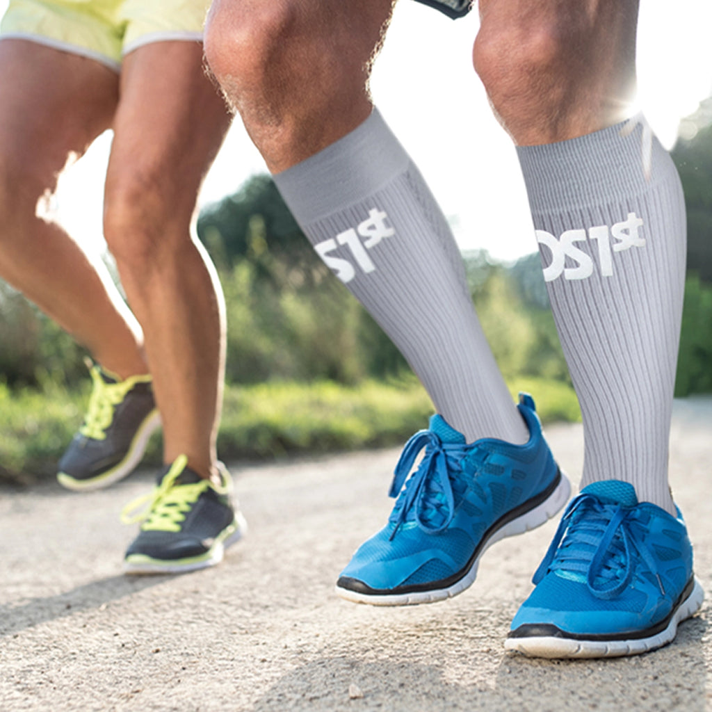 A close up of a male runner's legs wearing the compression bracing socks in grey