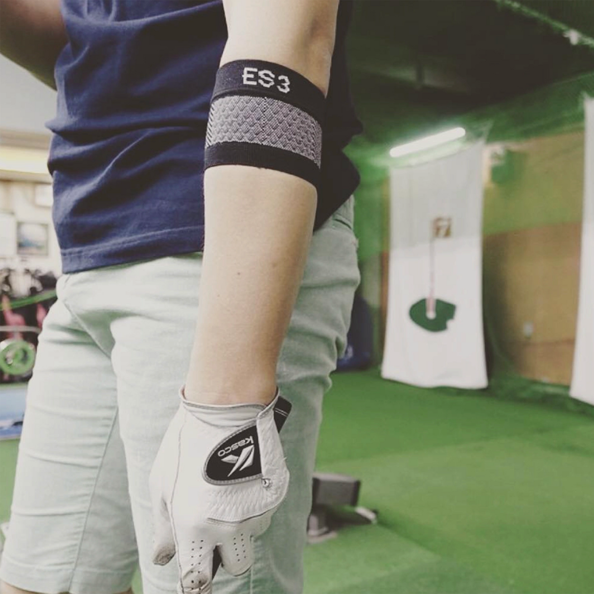 Woman golfing while wearing the compression elbow brace