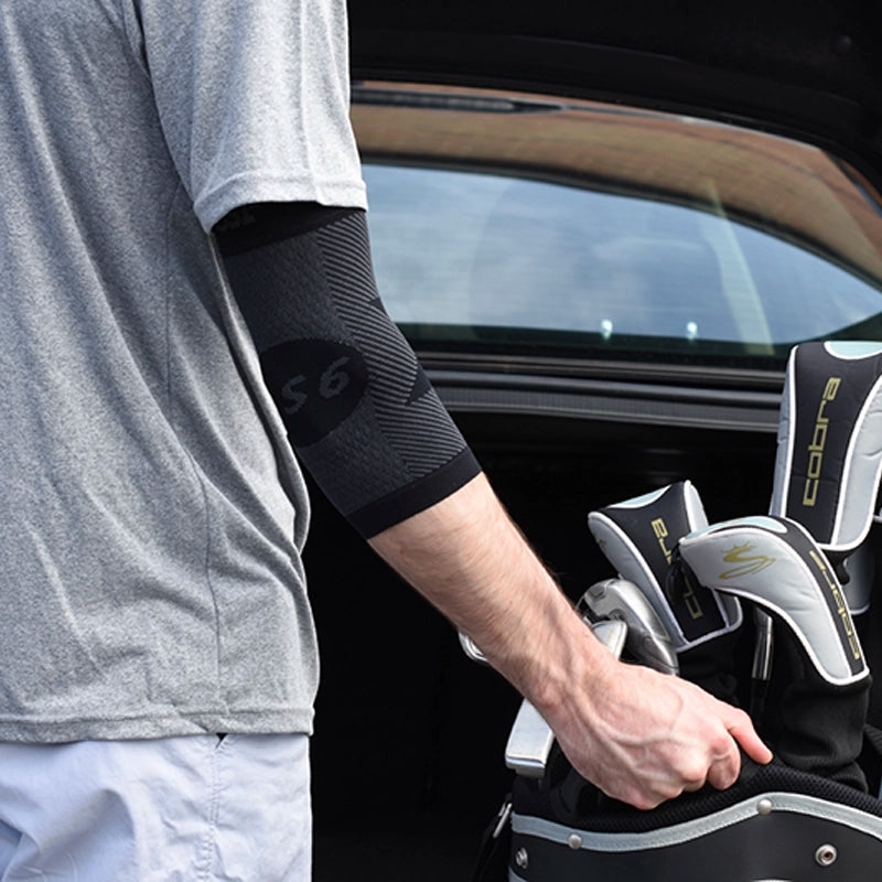 A man getting his golf clubs out of his trunk while wearing the black compression elbow sleeve
