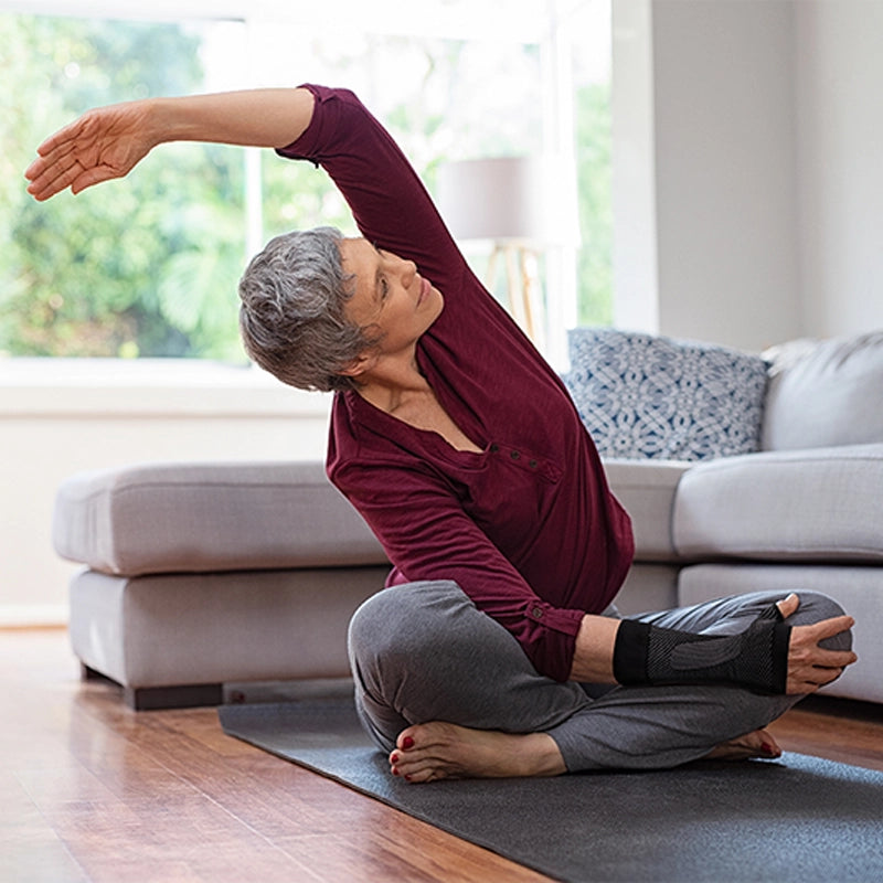Woman wearing the wrist compression sleeve to reduce wrist pain and swelling while doing yoga